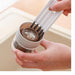 Person using a kitchen scrubber to clean a glass container with a strainer.