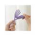 Purple hairbrush with heart design held by a hand against a white background
