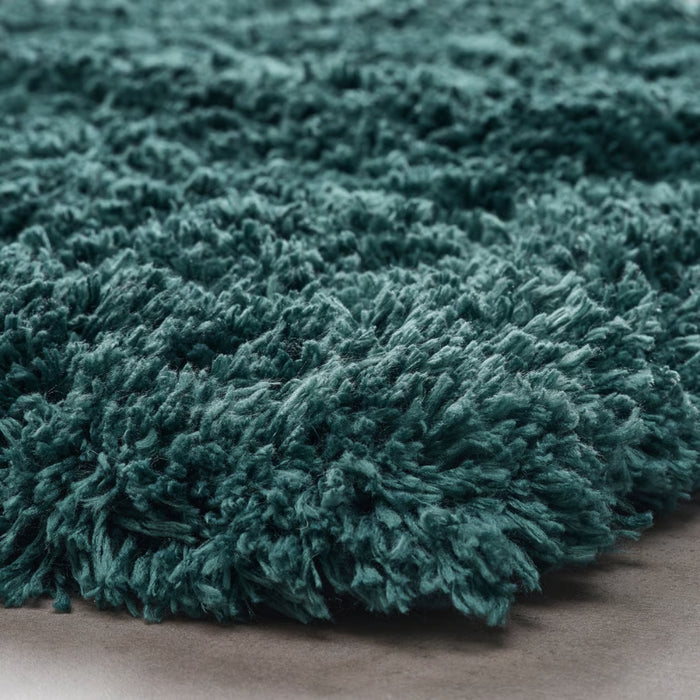 Close-up of a teal shaggy rug on a neutral background