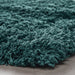 Close-up of a teal shaggy rug on a neutral background
