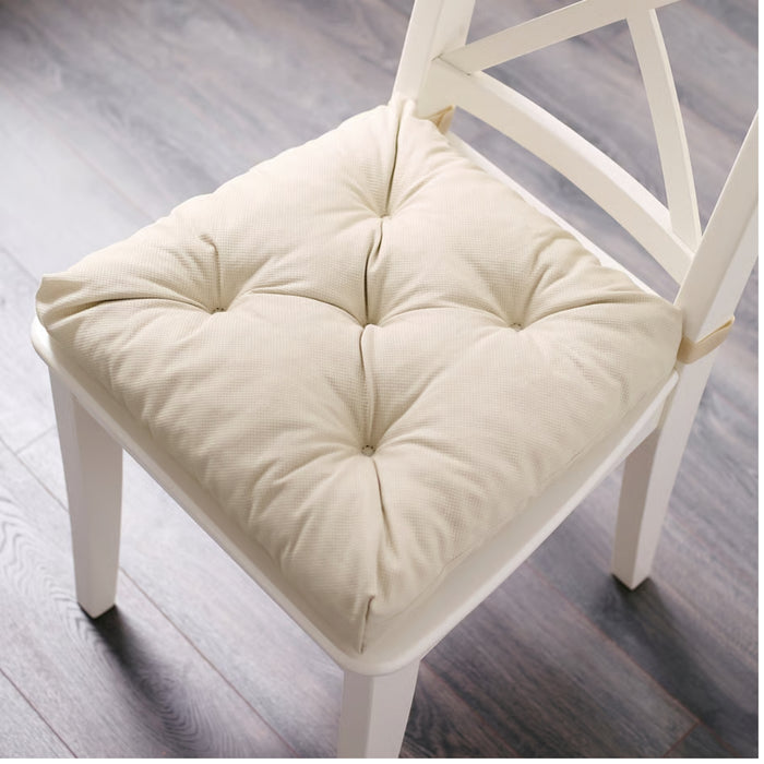 White wooden chair with a light beige IKEA VILDAURIKEL chair cushion, featuring a tufted quilted design with stitched buttons and a soft fabric texture—ideal for adding comfort and style to dining chairs and home decor -20559742.
