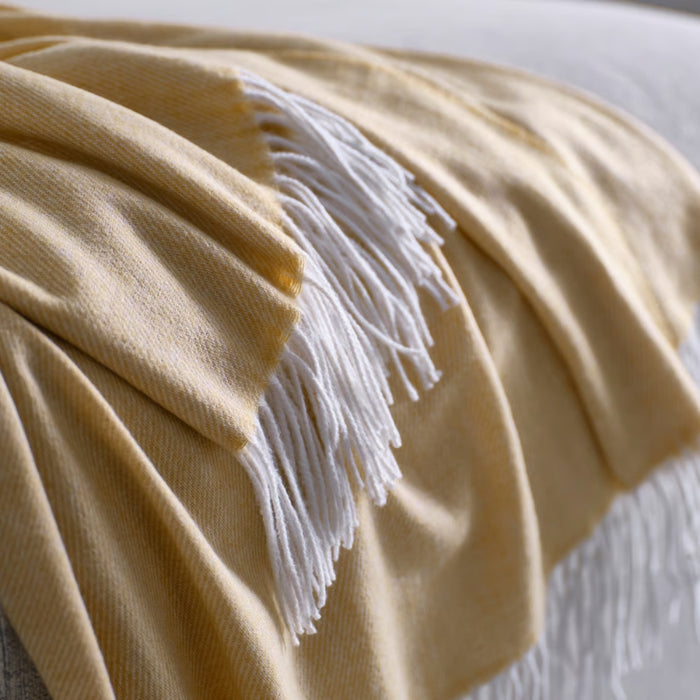 Beige blanket with white fringe on a light background