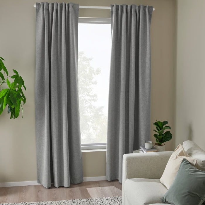 Gray curtains in a room with a beige wall, white sofa, and a plant.