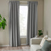 Gray curtains in a room with a beige wall, white sofa, and a plant.