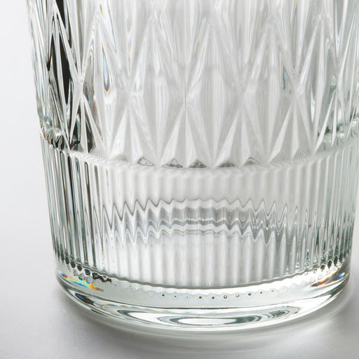 Close-up of a clear glass with intricate cut patterns on a white background