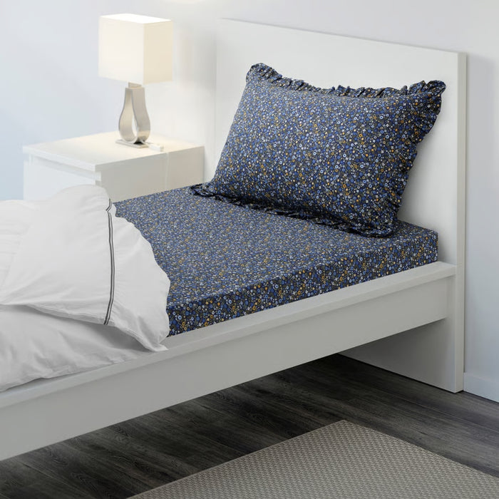 Bed with blue floral-patterned bedding and white pillows in a bedroom setting.