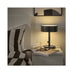 Black table lamp on a nightstand next to a bed with striped bedding.
