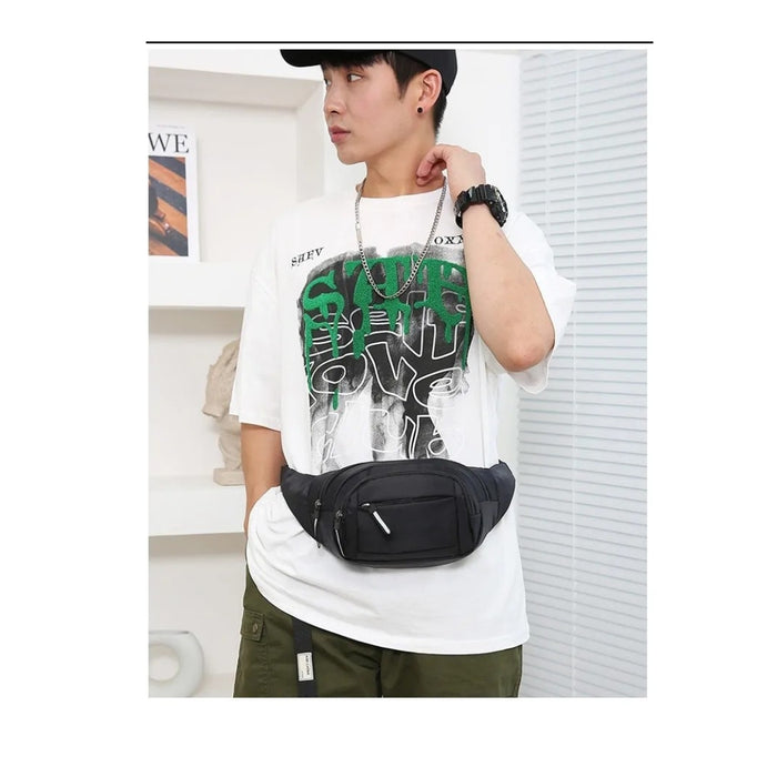 Person wearing a white t-shirt with green text and a black waist bag indoors.