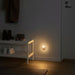 Warmly lit bulb-shaped nightlight plugged into a wall socket in a hallway, softly illuminating a shoe rack with boots and sneakers, a hanging coat, and a wooden floor with a textured mat.