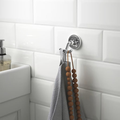 Bathroom hook with towel and beads on a tiled wall