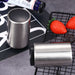 Two Bottle Openers on a black surface with strawberries and a bottle in the background.