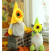 Two decorative gnomes with sunflower hats on a wooden surface.