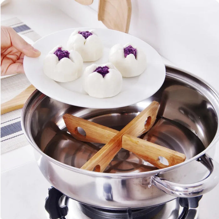 A person lifting a white plate of four steamed buns filled with purple paste—plate is held above a stainless steel pot on a gas stove, inside which lies a wooden cross-shaped bamboo steamer mat supporting the buns during cooking—visually showcases the steaming process using a traditional insulation rack – 562152 12826862.
