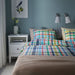 Bedroom with a colorful checkered bedspread and nightstands.