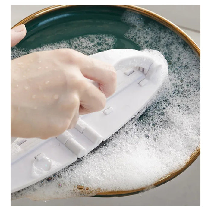 Hand using a scrubber to clean a soapy dish