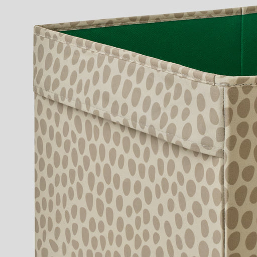 Storage bin with beige patterned exterior and green interior on a light gray background