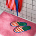 IKEA SKOGSSALLAT Slippers, red/white striped, L/XL, placed on a pink textured bath mat. The bold-striped design features a soft green insole and blue trim.-90596053
