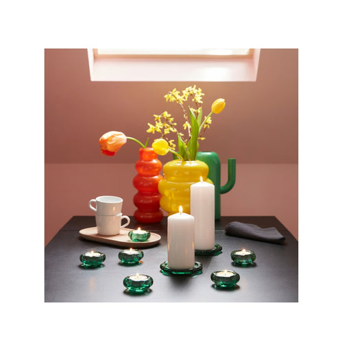 Colorful glass vases and candle holders on a table with a neutral background