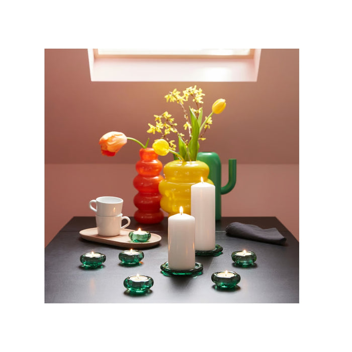 Colorful glass vases and candle holders on a table with a neutral background