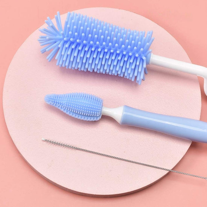 Set of cleaning brushes including a blue bottle brush, a white and blue straw brush, and a metal cleaning tool on a pink circular mat.