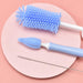 Set of cleaning brushes including a blue bottle brush, a white and blue straw brush, and a metal cleaning tool on a pink circular mat.