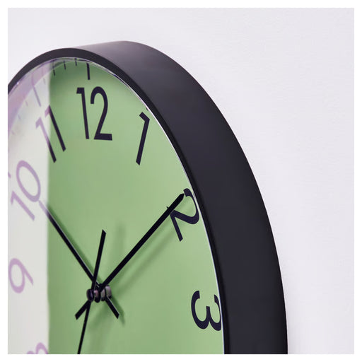 Wall clock with green face and black frame on a white background