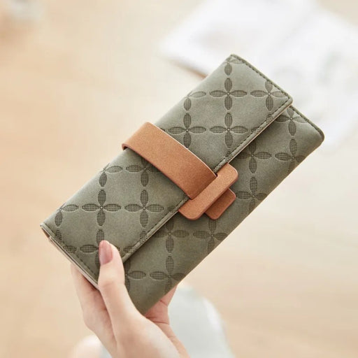 Green women’s wallet – hand holding purse with floral-like grid design and light brown tab strap