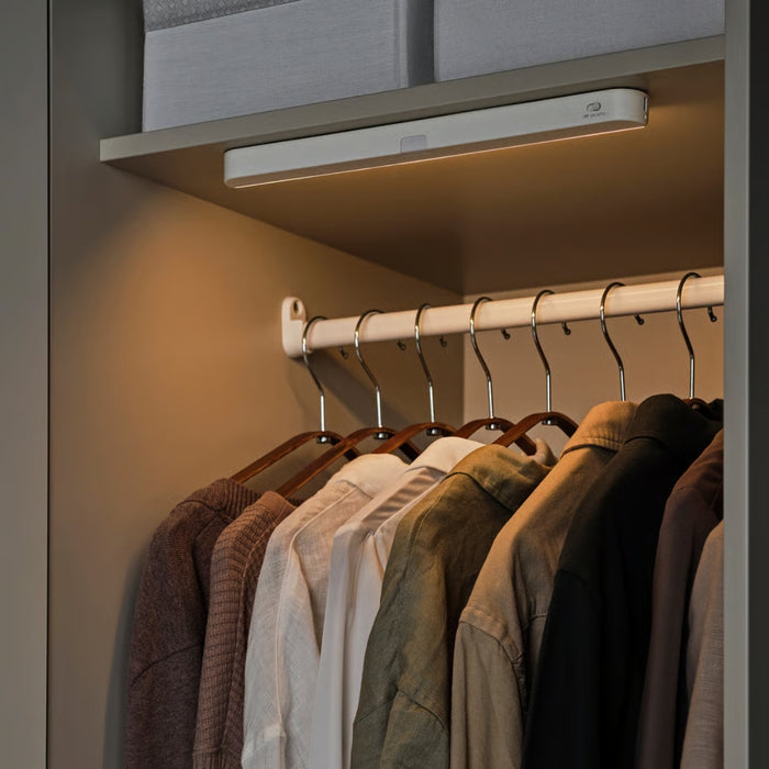 Closet with hanging clothes and a light fixture above