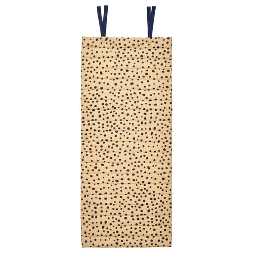 Beige version of SANDLÖPARE mat with irregular black dot pattern, quilted texture, and dark blue loops for hanging