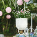 IKEA FEJKA artificial baby’s breath pink flowers in white hanging planter, outdoor garden setting with lanterns"