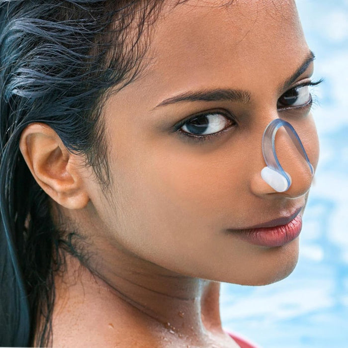 Person with wet hair wearing nose clip near swimming pool, showcasing aquatic use - 