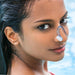 Person with wet hair wearing nose clip near swimming pool, showcasing aquatic use - 