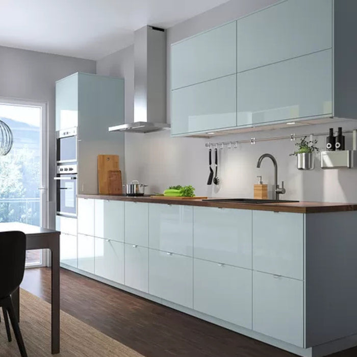 Modern kitchen with light blue cabinets, wooden countertops, and stainless steel appliances.