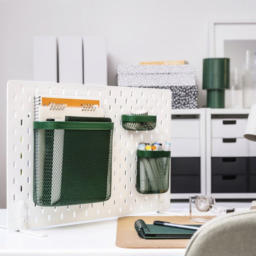 IKEA SKÅDIS green mesh storage basket set of 3 mounted on white pegboard; organizing notebooks, pens, tape, and glue in creative workspace – ideal for tidy desk setup and efficient office storage - 20597471