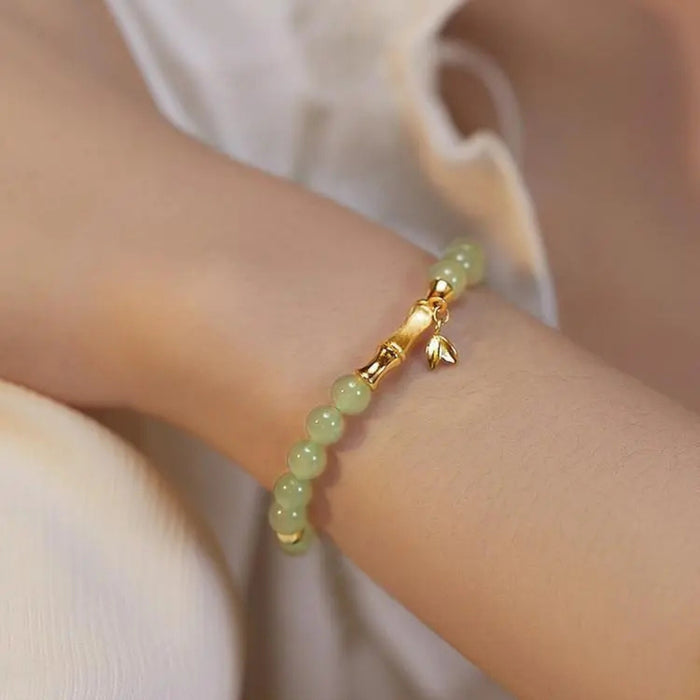 Green beaded bracelet with gold accents on a wrist against a neutral background