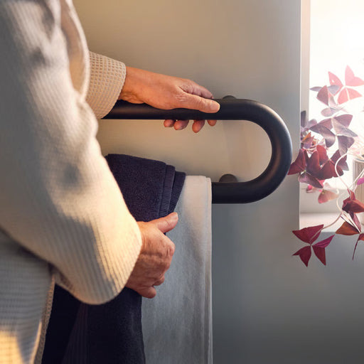 Person using a black handrail on a staircase with a soft focus background