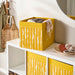 IKEA DRÖNA Box in dark yellow with white wavy-line design, neatly placed on a white shelf, storing folded clothes and accessories—ideal for stylish home organization.-00603331