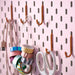 IKEA SKÅDIS hook set in orange (5-pack) mounted on pink pegboard; organizing USB cable, decorative tape rolls, and white scissors – ideal for craft room or office wall storage - 00606136
