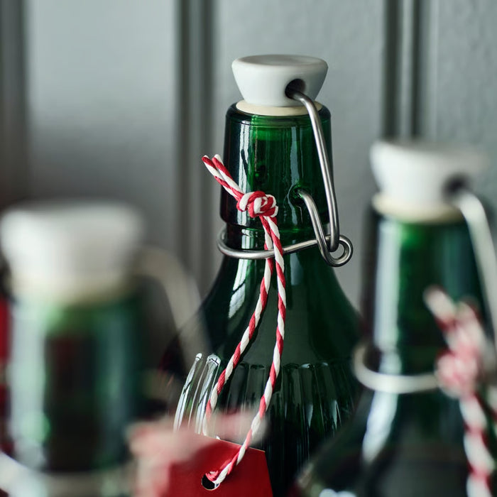 Green bottles with white caps and red string, blurred background