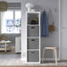 White storage unit with gray bins in a room with a window, chair, and stool.