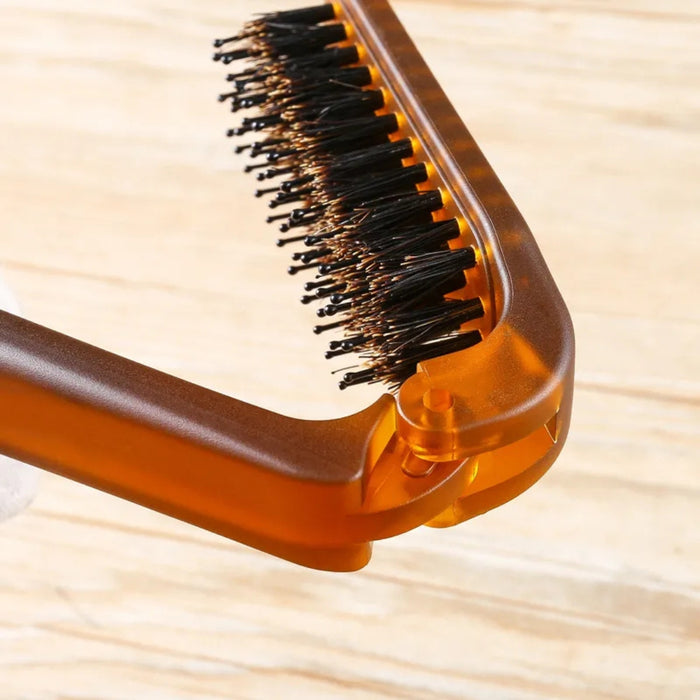 Close-up of a brown hairbrush with black bristles on a wooden surface