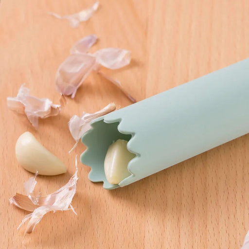 Silicone garlic peeler on a wooden surface with peeled garlic cloves.