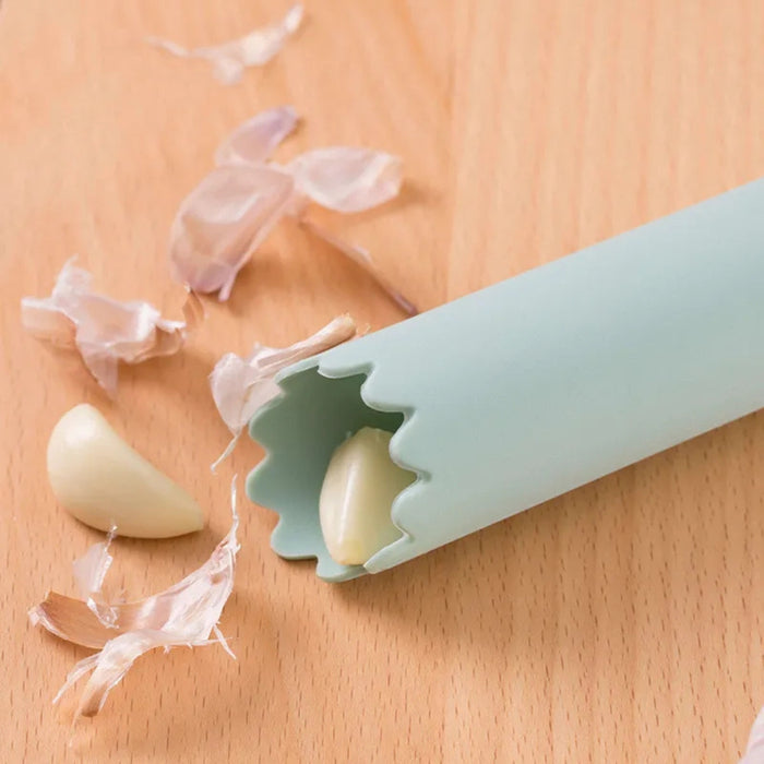 Silicone garlic peeler on a wooden surface with peeled garlic cloves.