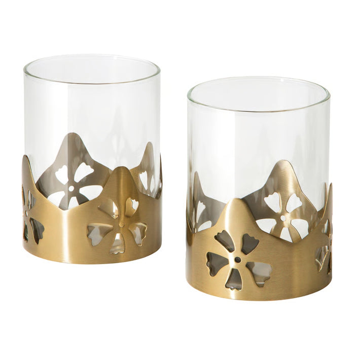 Two AROMATISK tealight holders featuring clear glass cylinders and elegant brass-finish floral decorative bases.