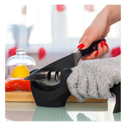 Person using a knife sharpener with a blurred kitchen background