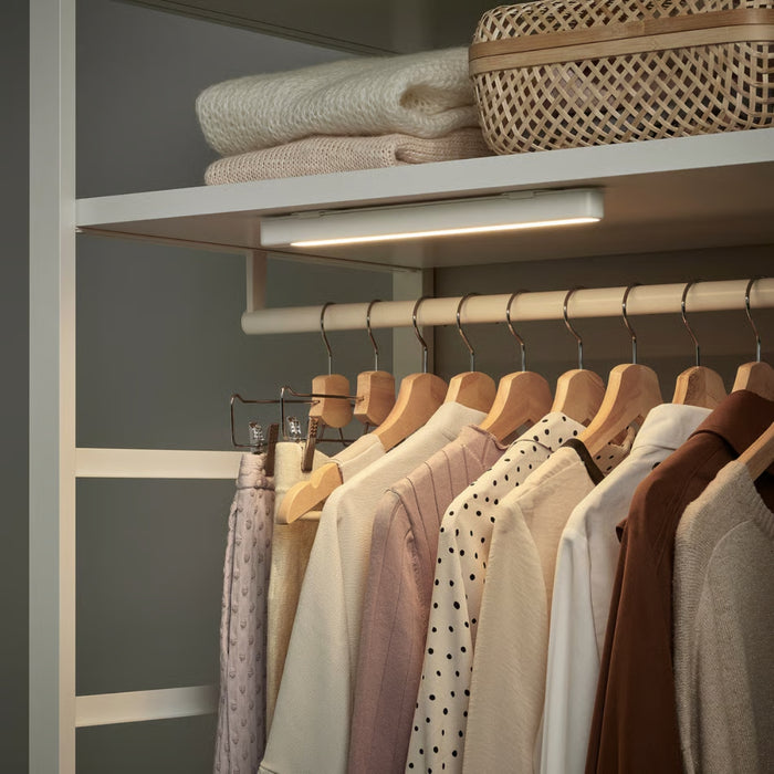 IKEA ROLFSTORP LED light bar installed inside a wardrobe, brightly illuminating organized clothes and baskets.