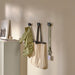 Three black cat-shaped wall hooks mounted on a beige wall, each holding different items: a jacket, tote bag, and lanyard. A stylish and functional storage solution adding personality to the space.-90567791