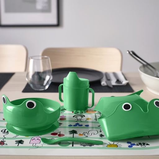 Green children's tableware set with a frog design on a dining table.
