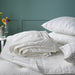 White bedding set on a bed with a teal wall in the background