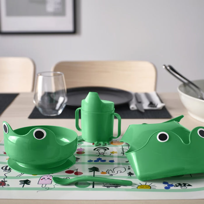 Green children's tableware set with a frog design on a dining table.